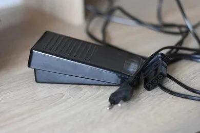 Foot pedal connected to a sewing machine used to control sewing speed.