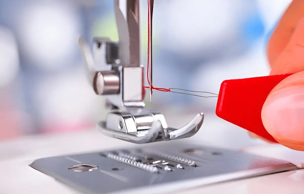 Close-up of a Janome sewing machine's automatic needle threader feature in action.